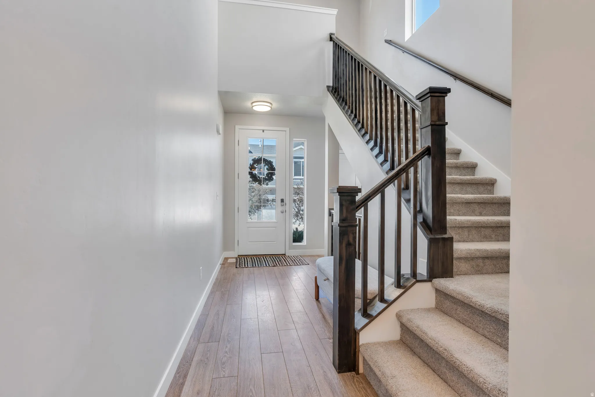 Entryway featuring wood-finish flooring and a staircase with dark wood railings and carpeted treads