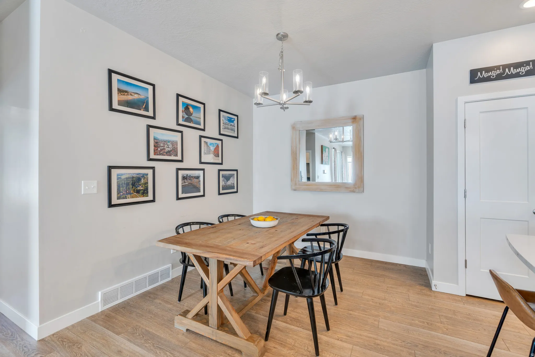 Dining area featuring wood-finish flooring, a contemporary chandelier, and a framed mirror