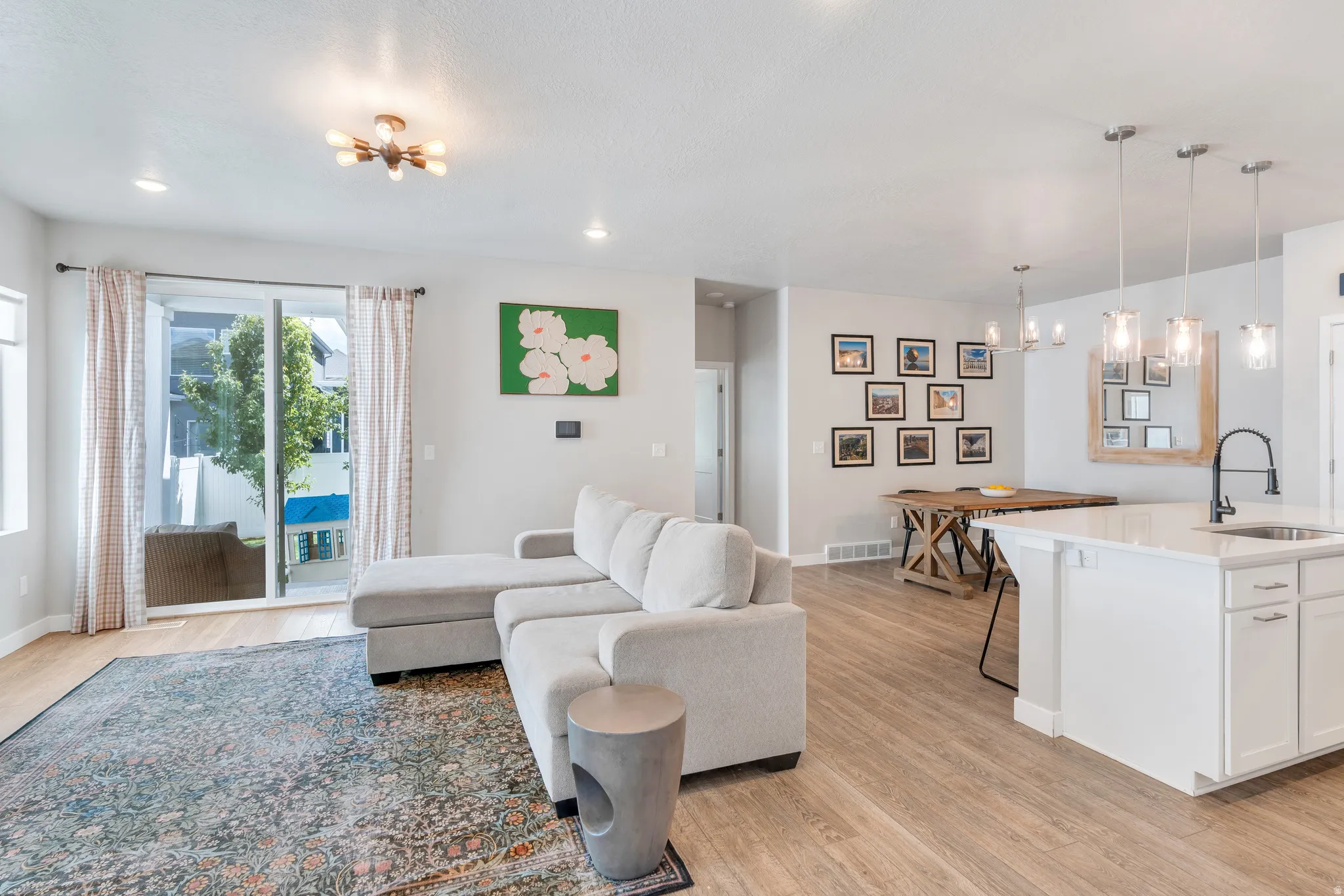 Open-concept living space featuring wood-finish flooring throughout, a sliding glass door for outdoor access, and recessed lighting