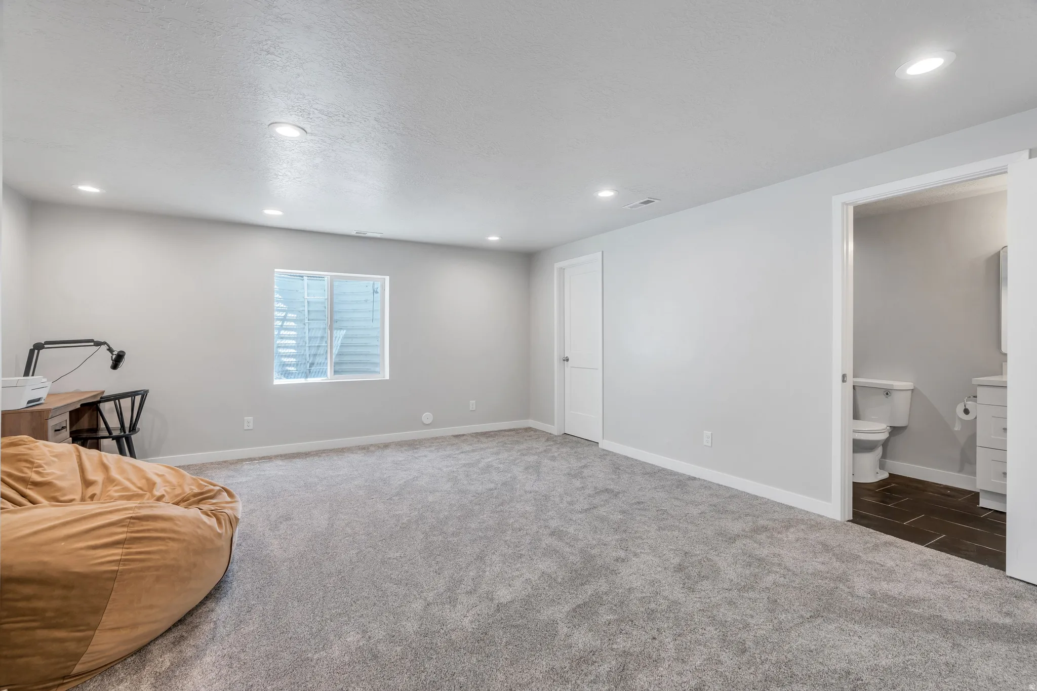 Spacious room with light gray carpeting and recessed lighting