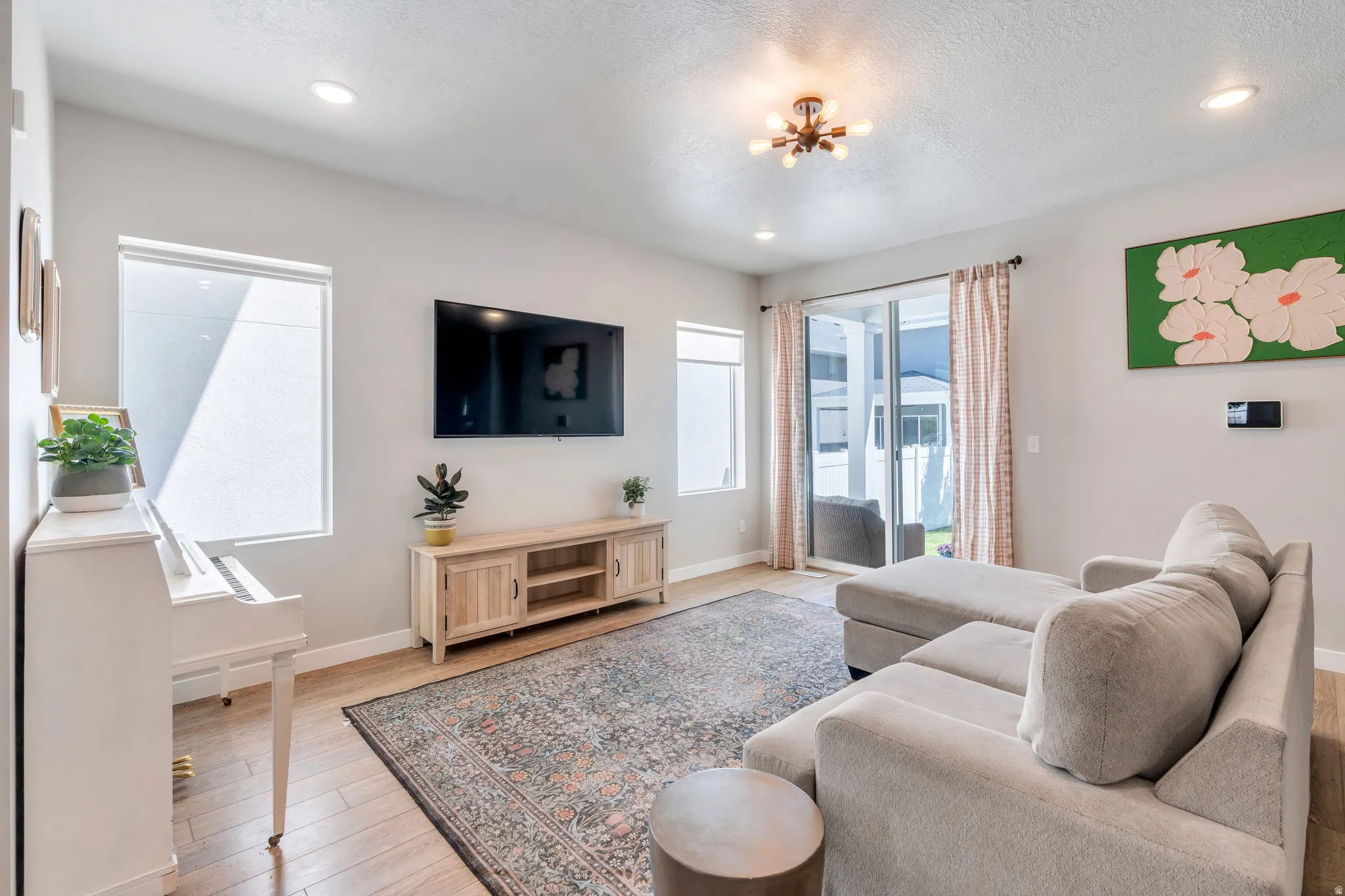 Spacious living area featuring light wood-finish flooring, recessed lighting, and a modern ceiling fixture