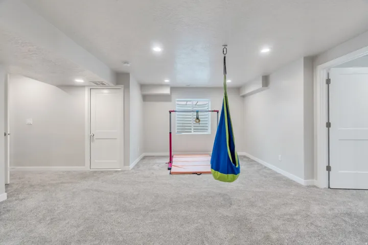 Spacious carpeted room featuring recessed lighting, white trim, and a window with white shutters