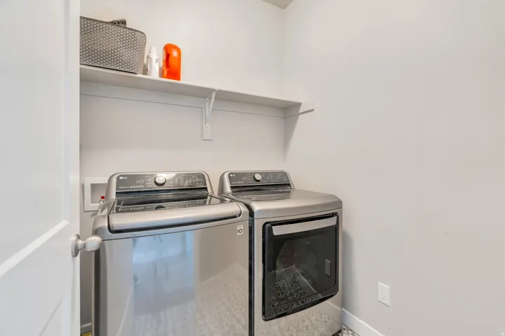 Dedicated utility area featuring a wall-mounted shelving unit, contemporary white walls, and a durable tile flooring