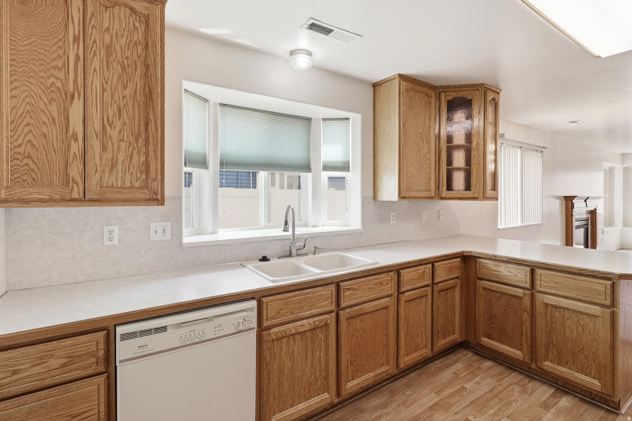 Kitchen featuring wood-finish cabinetry, a double basin sink, and a bay window