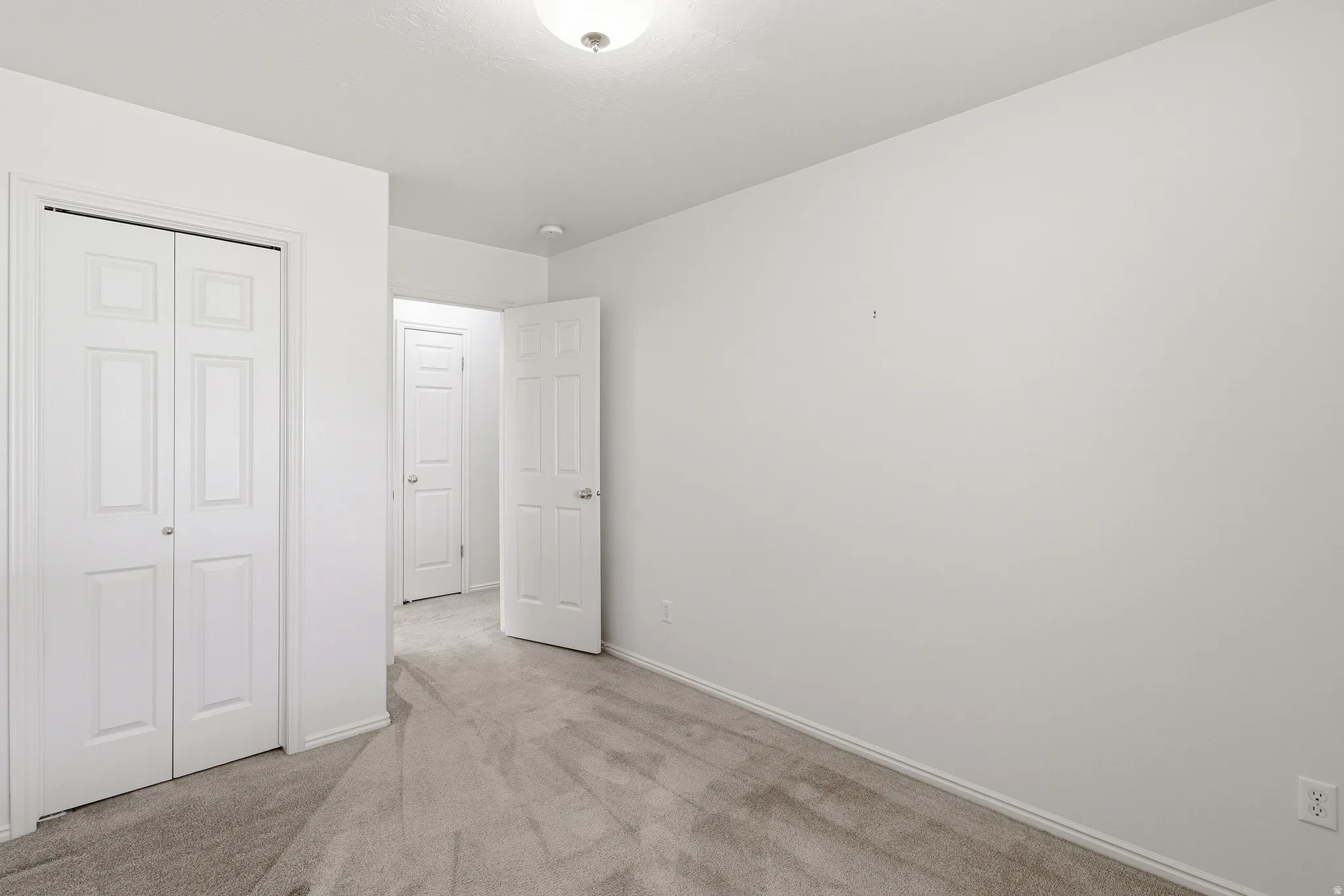 Carpeted room featuring white walls, a bi-fold closet, and base molding
