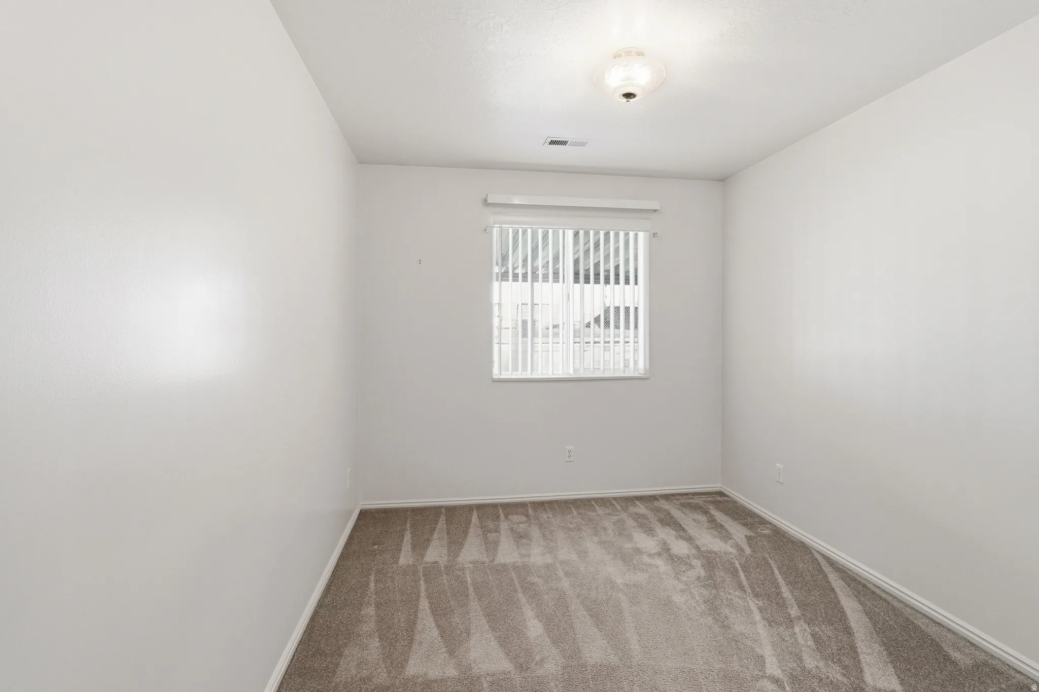 Room featuring neutral wall tones, textured carpet, window with horizontal blinds, and a flush mount ceiling light fixture
