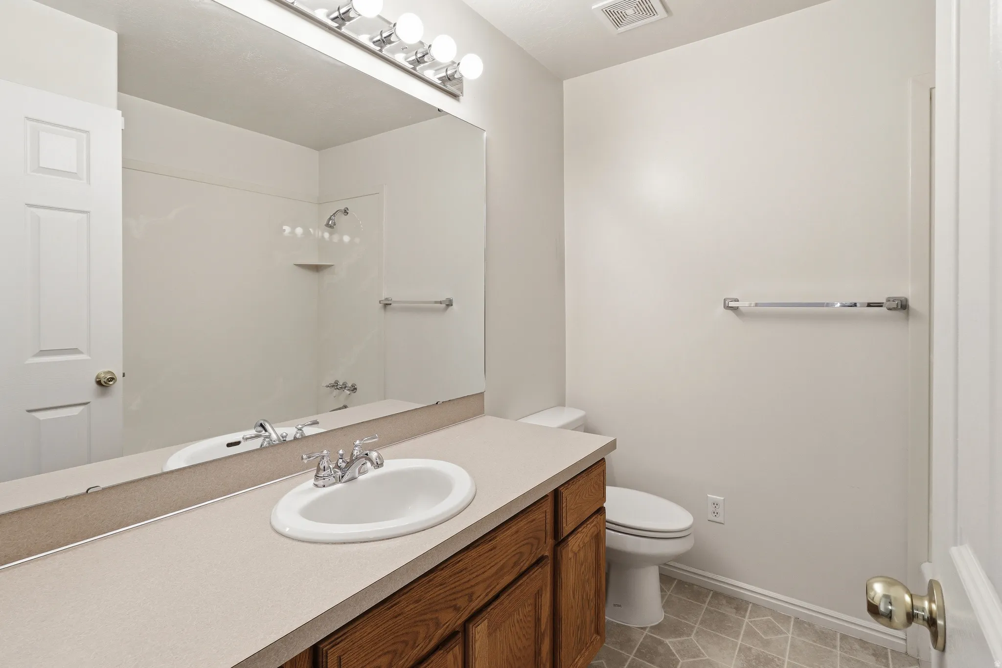 Full vanity with an integrated sink, wood-finish cabinetry, and a large wall-mounted mirror