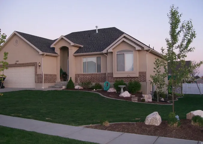 Stucco and brick exterior with a dark shingle roof