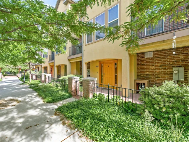 Stucco exterior with a vibrant yellow entry door and front patio featuring wrought iron fencing