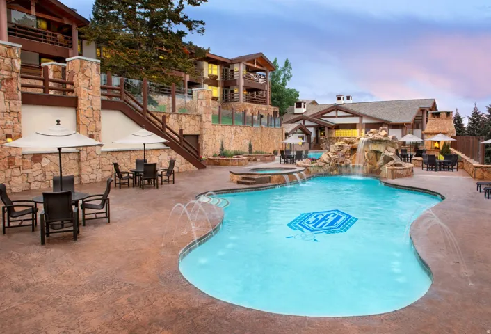 Resort-style pool area featuring a freeform pool with integrated spa and rock waterfall