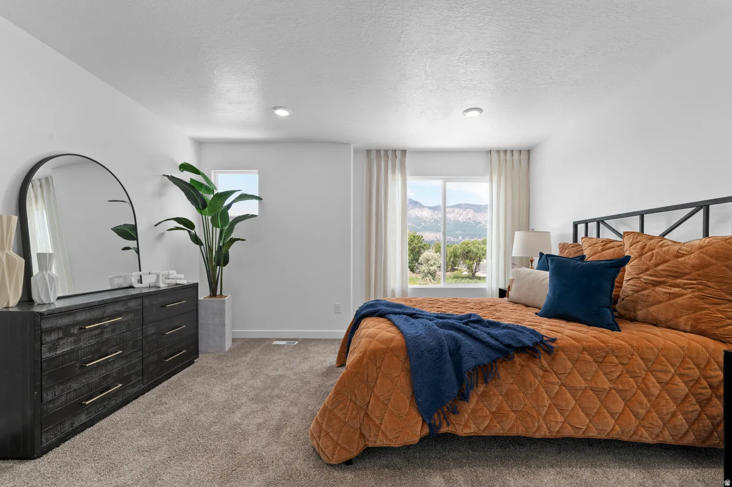 Carpeted bedroom featuring recessed lighting, a large window with mountain scenery, and white window treatments