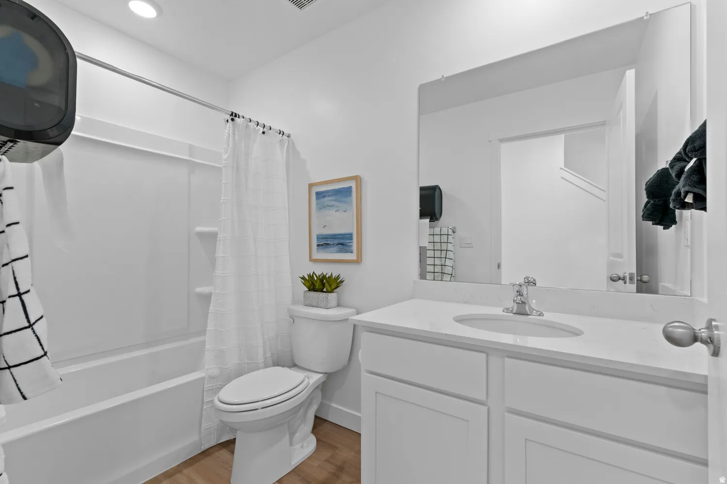 Full bathroom featuring a white vanity with an integrated sink, a large mirror, and a full-size bathtub with a shower