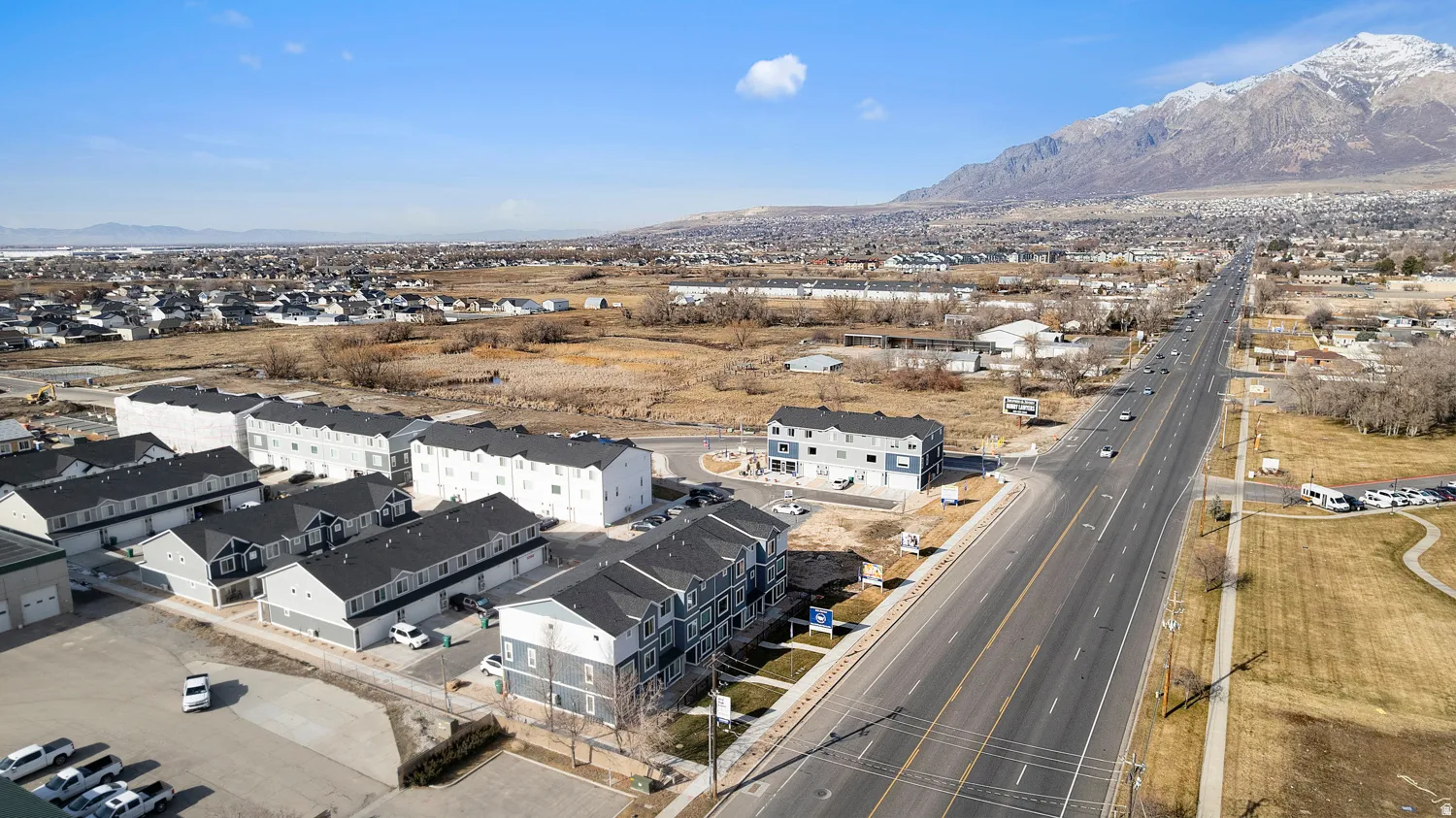 Aerial perspective showcasing multiple two-story and three-story townhome buildings with dark gray and white exteriors