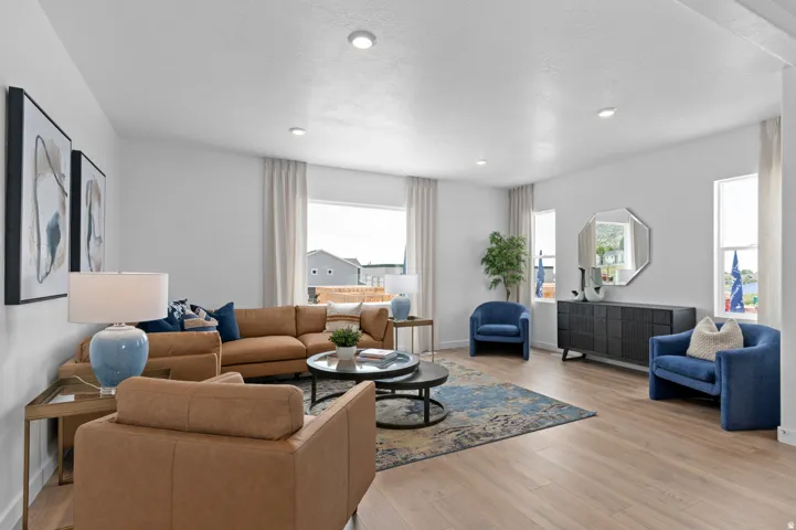 Spacious living area featuring light wood-finish flooring and ample natural light from multiple windows