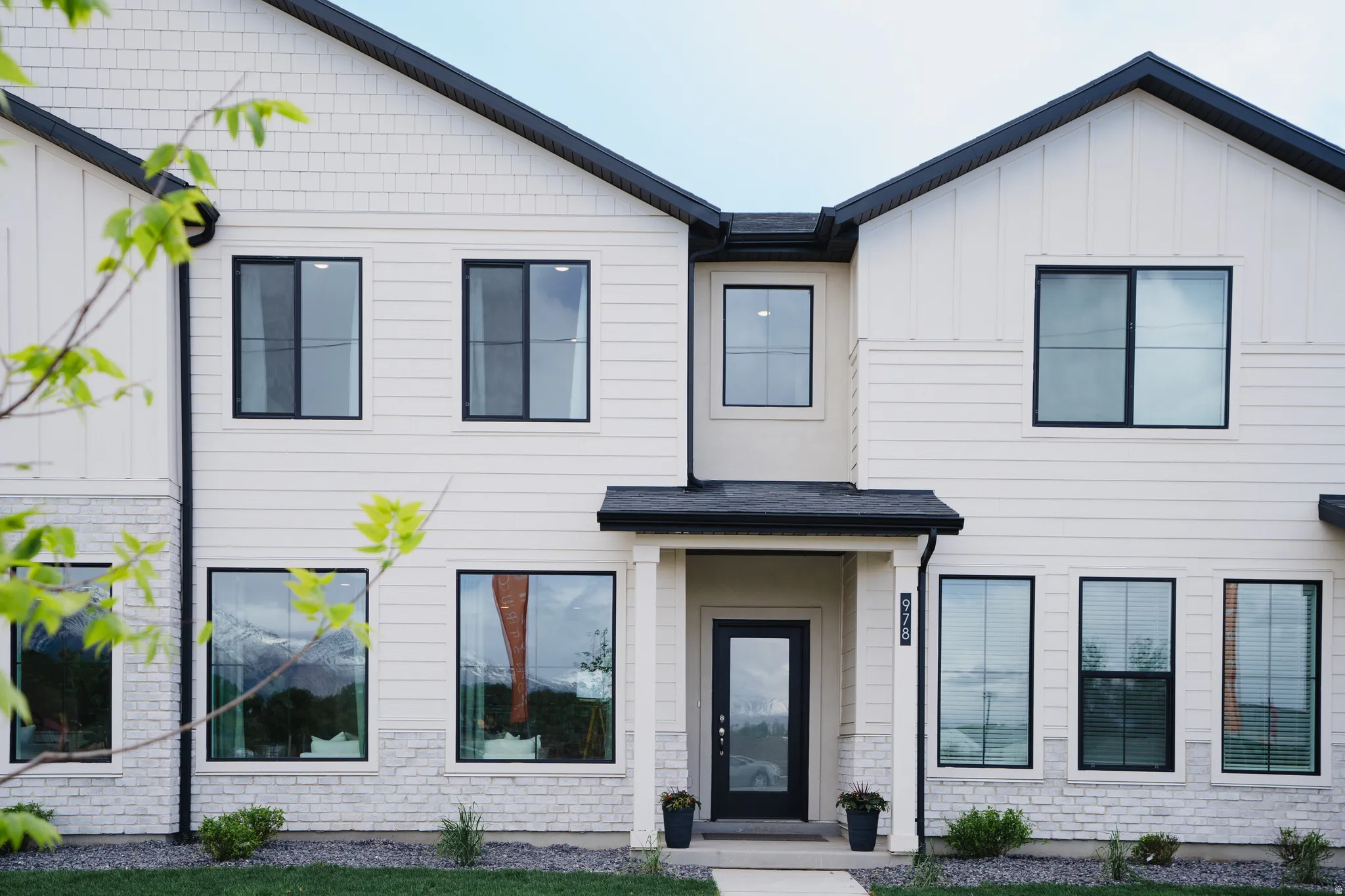 Modern two-story facade with white siding and brick accents