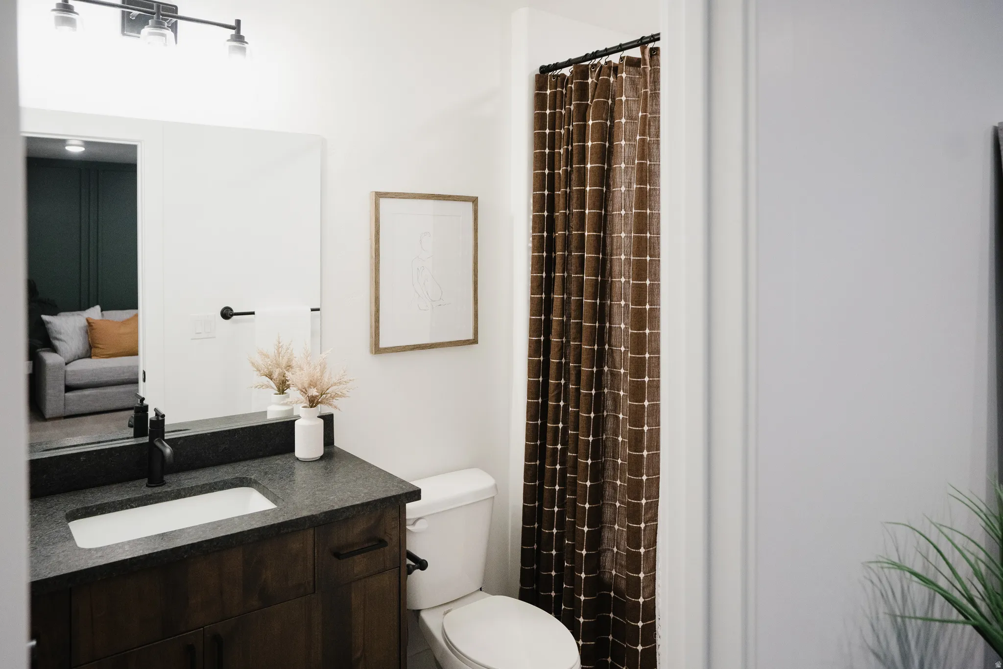 Bathroom featuring a dark wood vanity with a black countertop, integrated rectangular sink, and matte black faucet