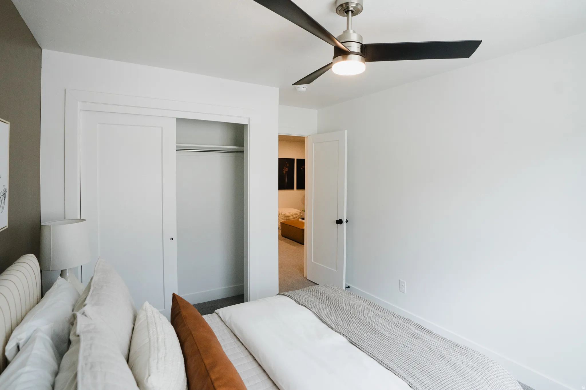 Contemporary bedroom with white walls and a ceiling fan with integrated lighting