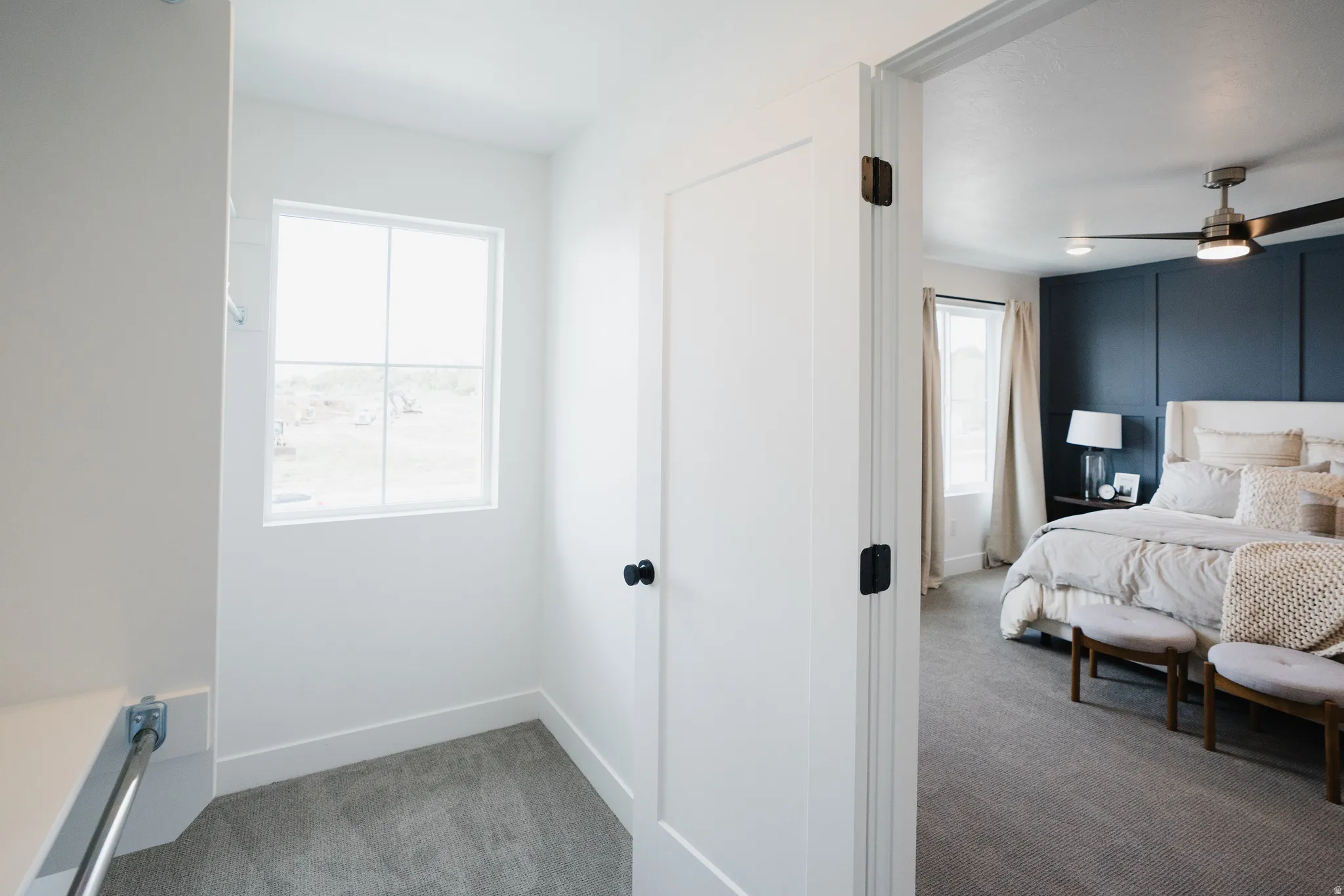 Bedroom featuring a dark accent wall with panel molding, a ceiling fan with integrated lighting, and carpet flooring
