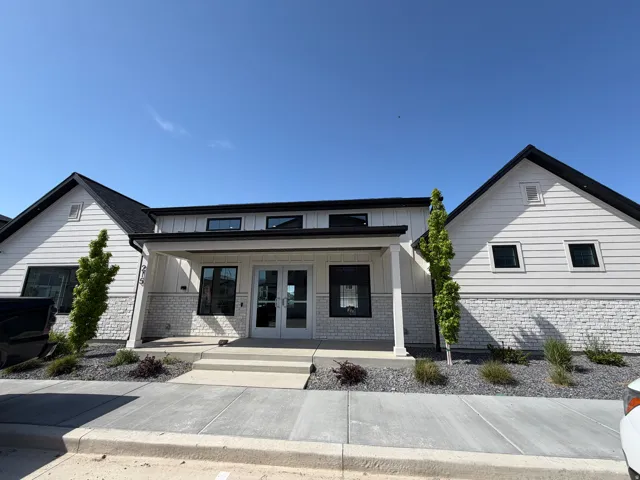 Modern farmhouse exterior featuring white vertical and horizontal siding, contrasting black trim, and a prominent covered entryway with double glass doors