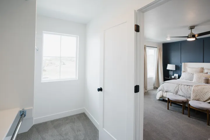 Bedroom featuring a dark accent wall with panel molding, a ceiling fan with integrated lighting, and carpet flooring