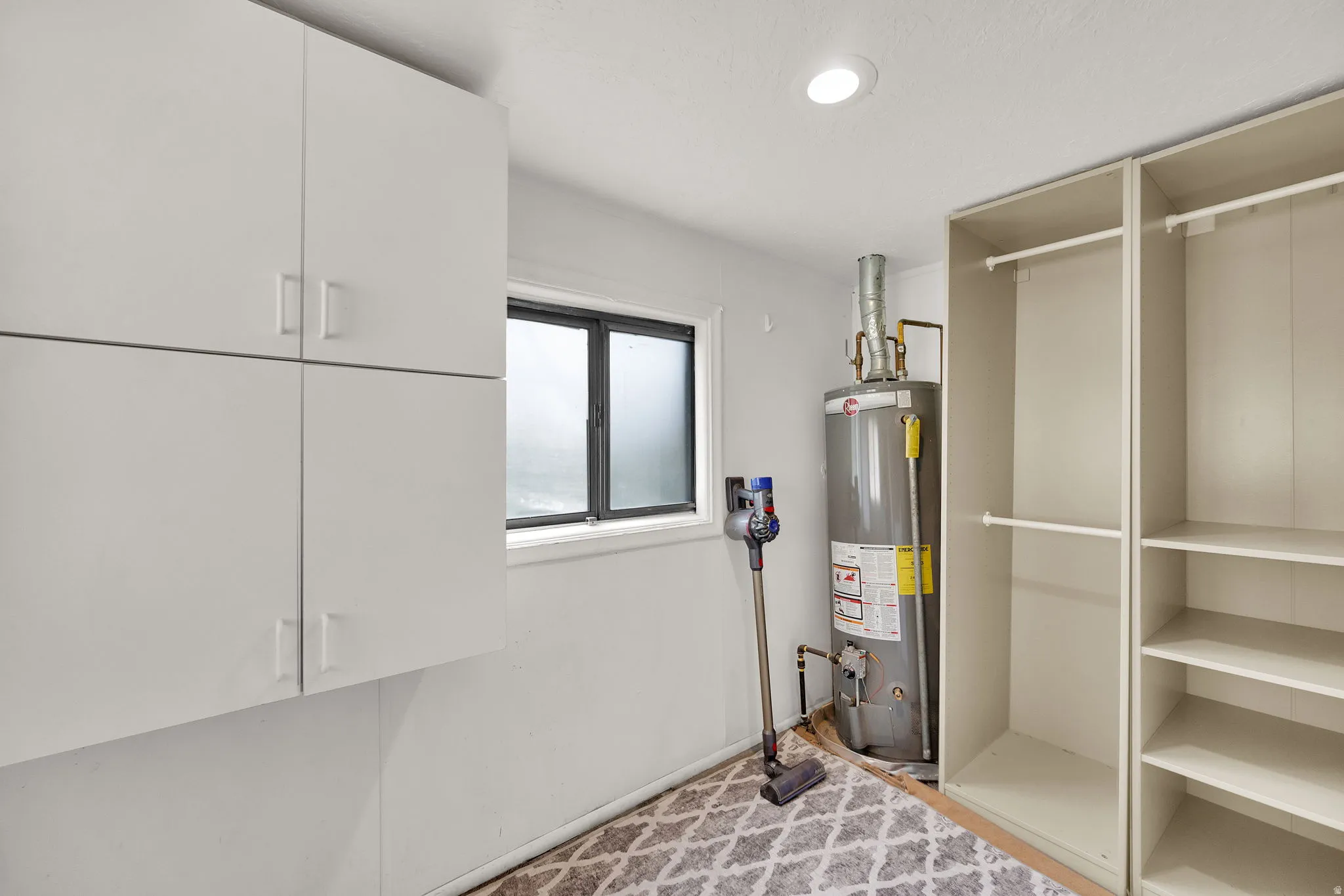 Built-in storage solutions featuring white cabinetry and an open shelving system with hanging rods
