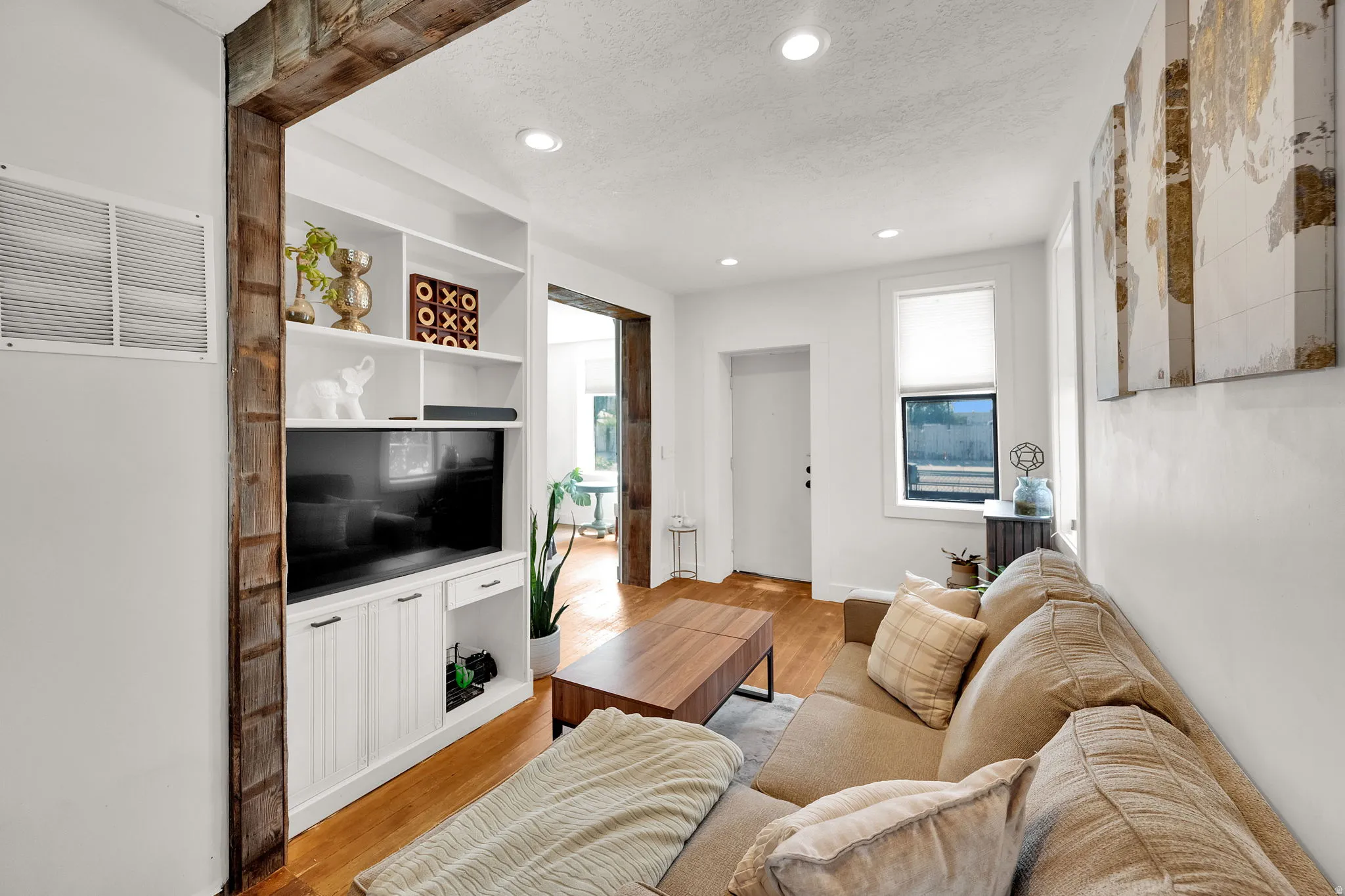 Living space featuring recessed lighting, hardwood flooring, and a built-in media center with shelving and cabinet storage