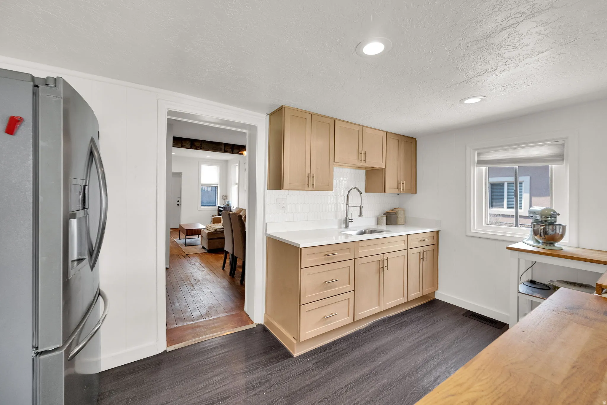 Kitchen featuring light wood-finish cabinetry, white subway tile backsplash, and a stainless steel sink with a gooseneck faucet