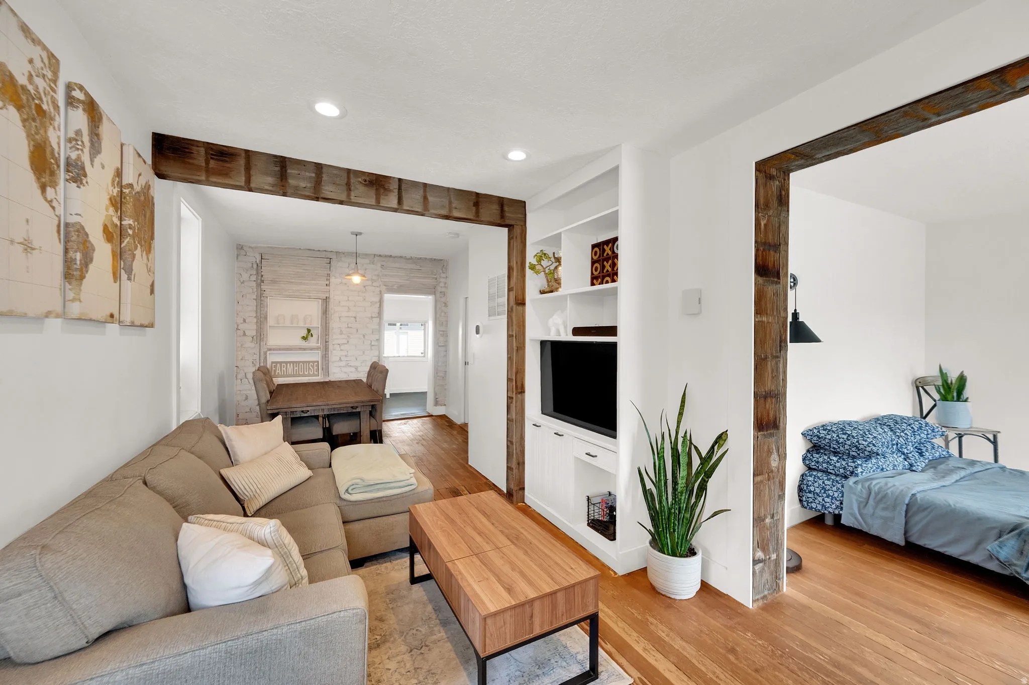 Open-concept living area featuring rich wood-finish flooring, recessed lighting, and exposed beam accents