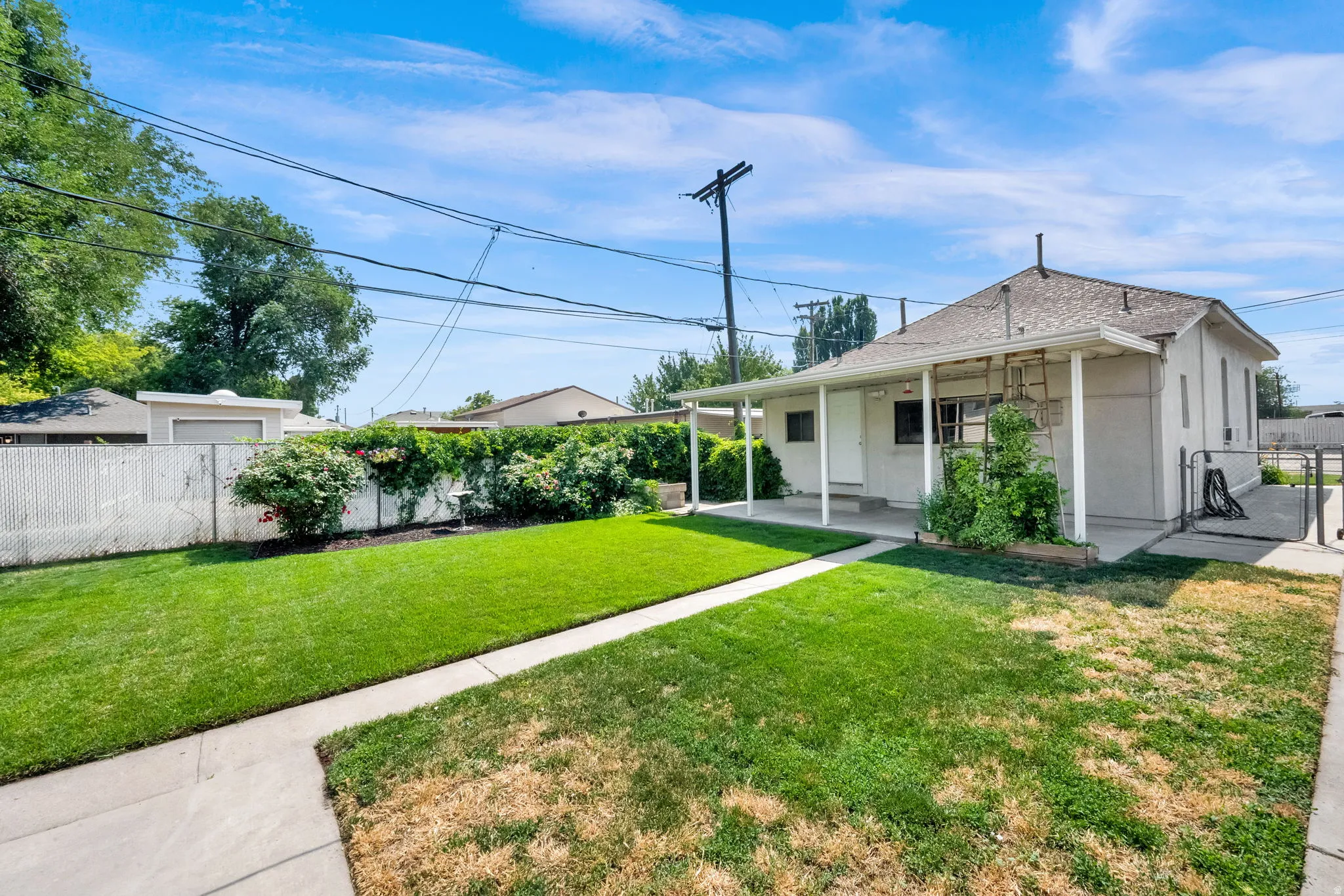 Expansive rear yard featuring a manicured lawn, concrete patio, and mature perimeter landscaping