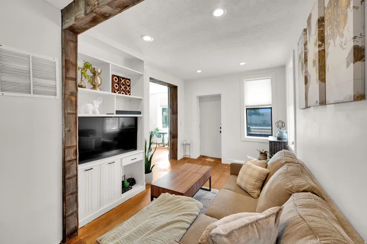 Living space featuring recessed lighting, hardwood flooring, and a built-in media center with shelving and cabinet storage