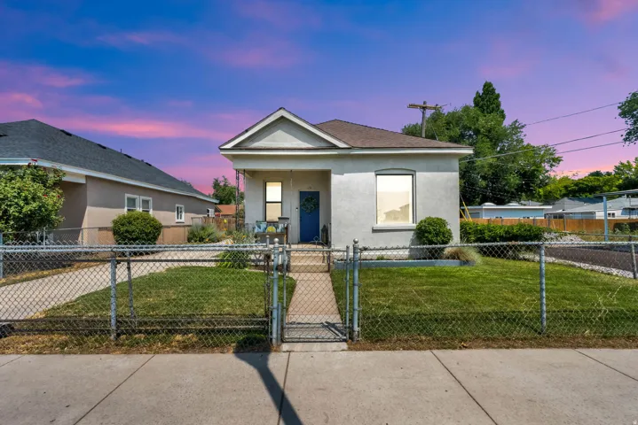Single-story residence featuring a front porch with an overhang, a blue entry door, and a front yard with chain-link fencing