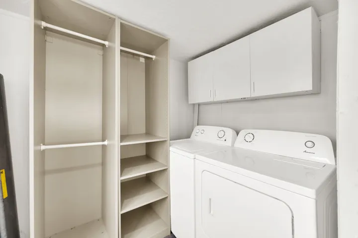 Laundry area featuring a side-by-side washer and dryer, white overhead cabinetry, and a built-in storage system with hanging rods and shelving