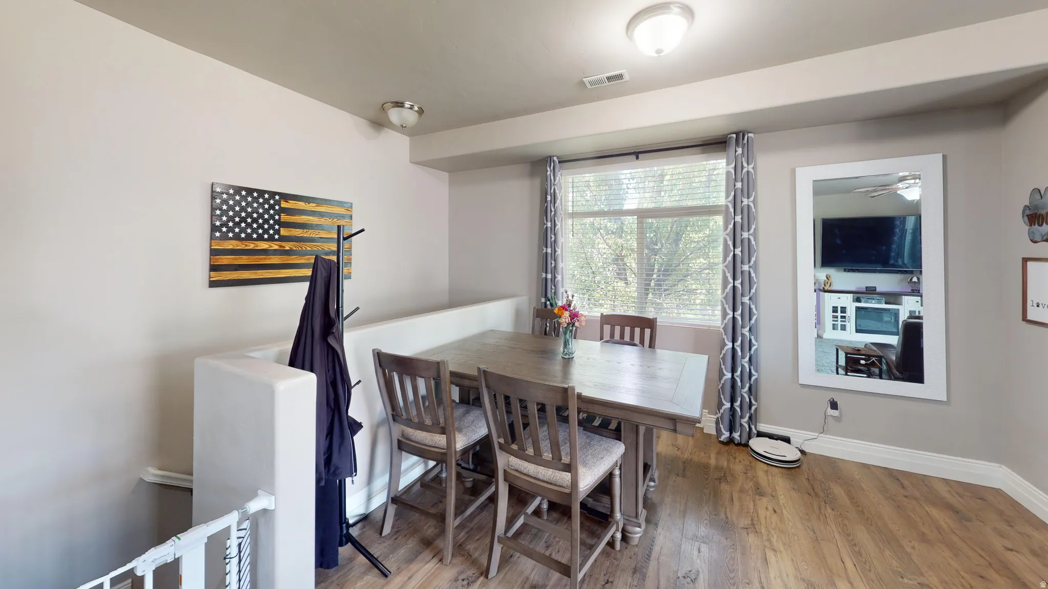 Spacious room featuring wood-finish flooring, a contemporary ceiling light fixture, and a large window with blinds