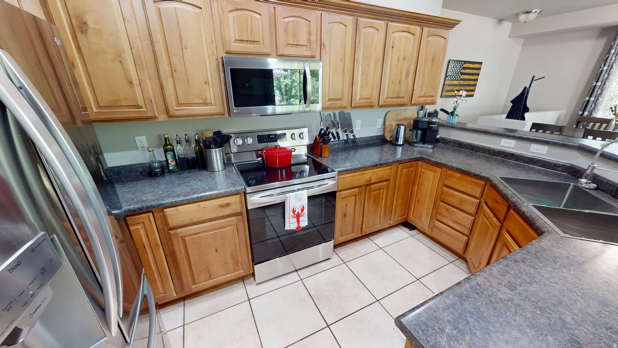 Kitchen featuring wood cabinetry, stainless steel appliances, a double basin sink, and tile flooring