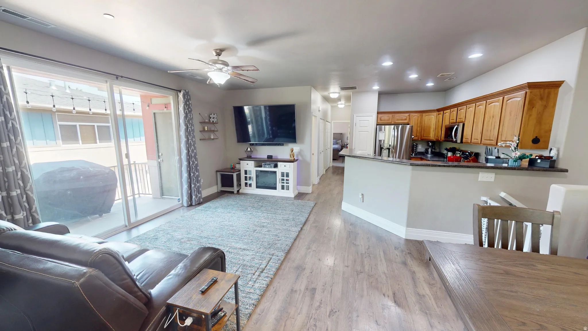 Open-concept living area featuring wood-finish flooring, recessed lighting, and a ceiling fan