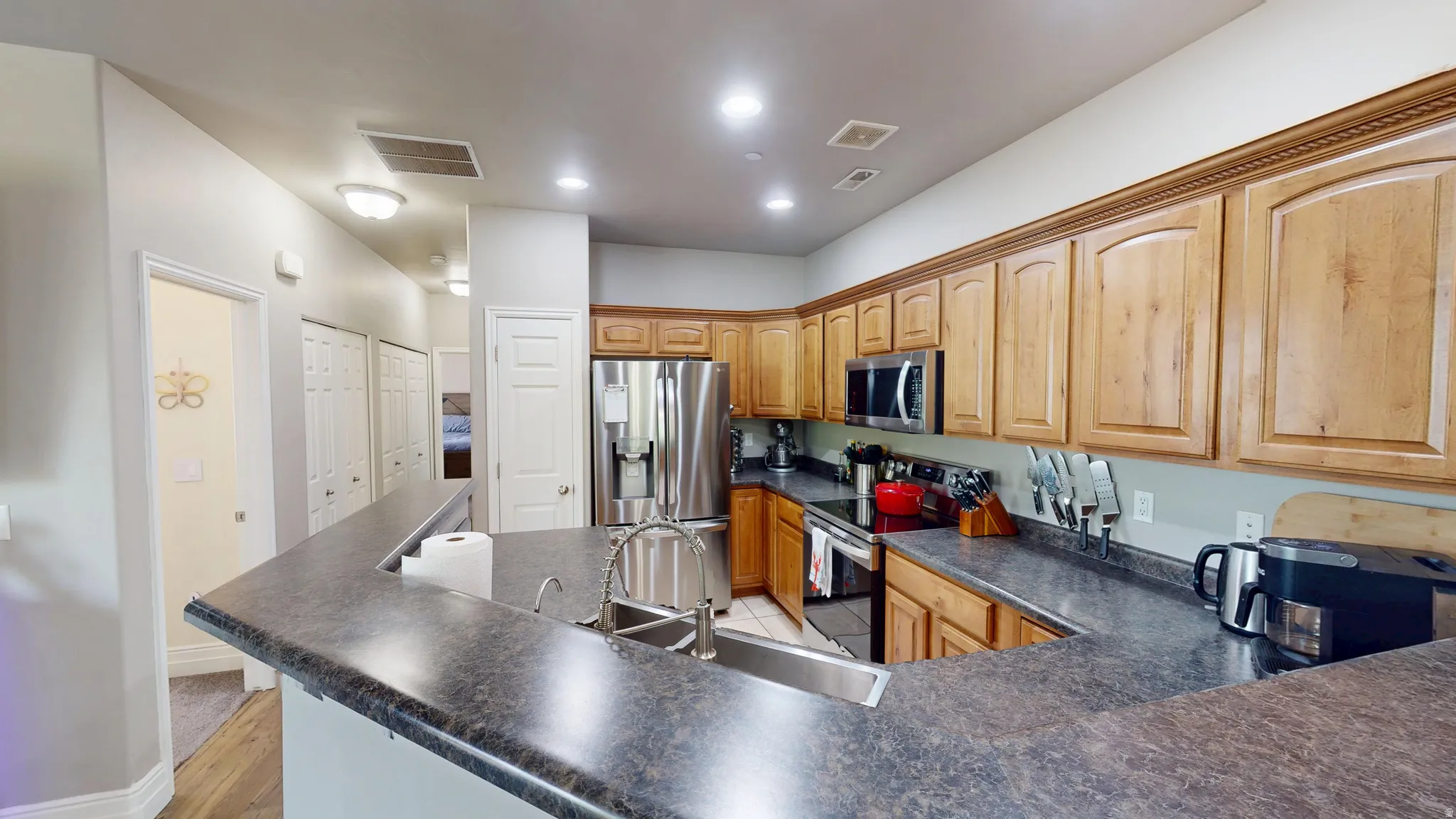 Kitchen featuring a U-shaped countertop with an integrated sink, natural wood cabinetry, and stainless steel appliances