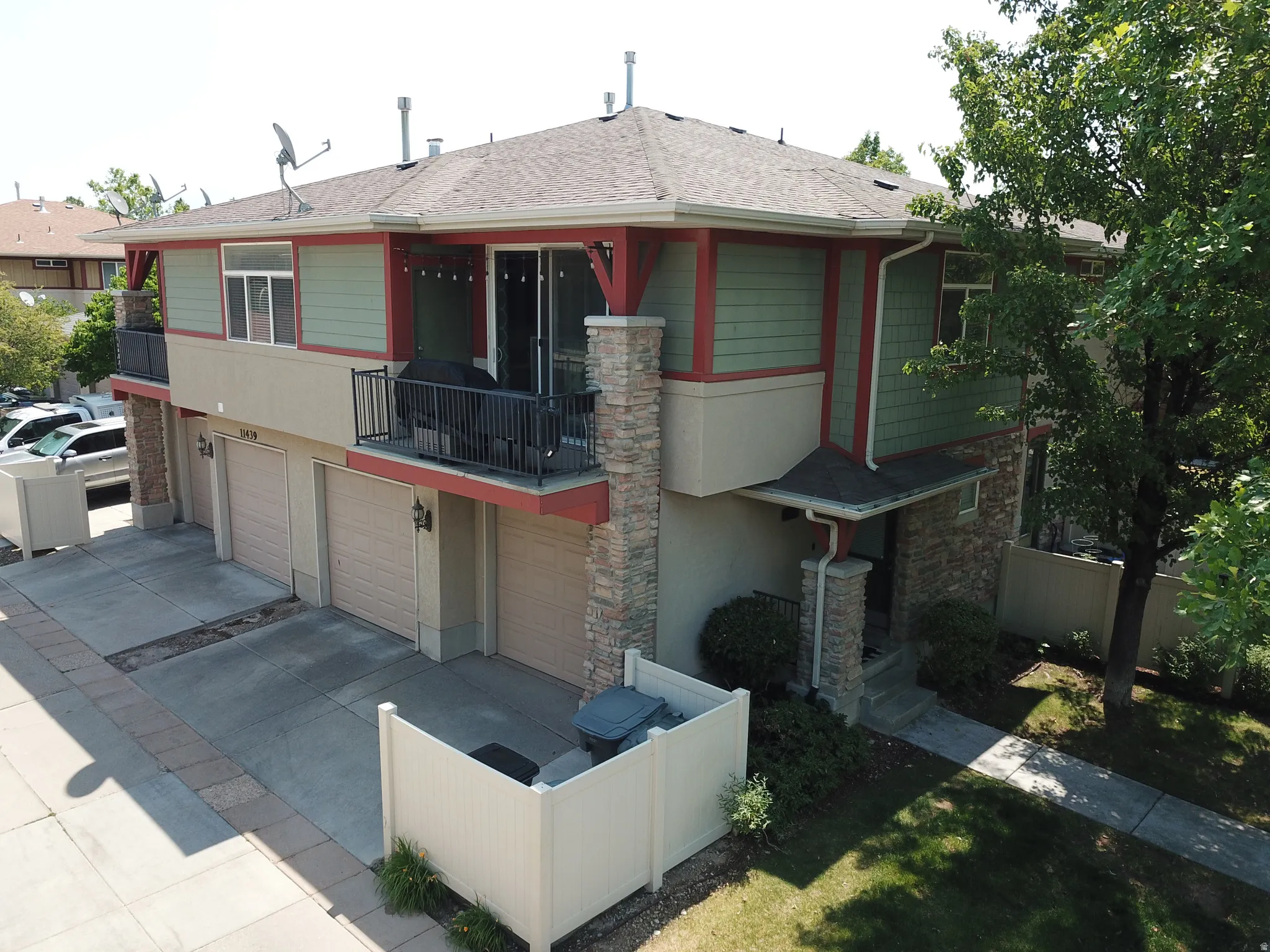 Multi-level exterior featuring a private balcony with wrought iron railing, two garage doors, and a stone-clad entry porch