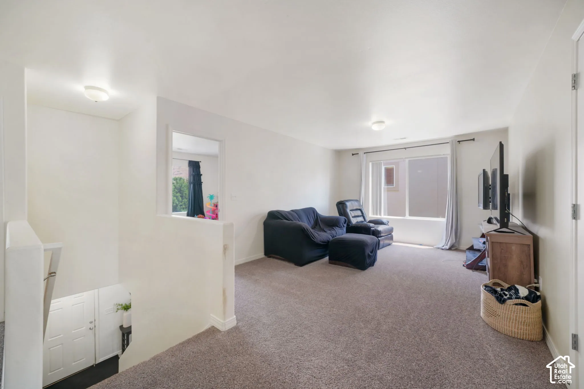 Carpeted living area featuring a large window, a partial wall opening, and a flush-mount ceiling light