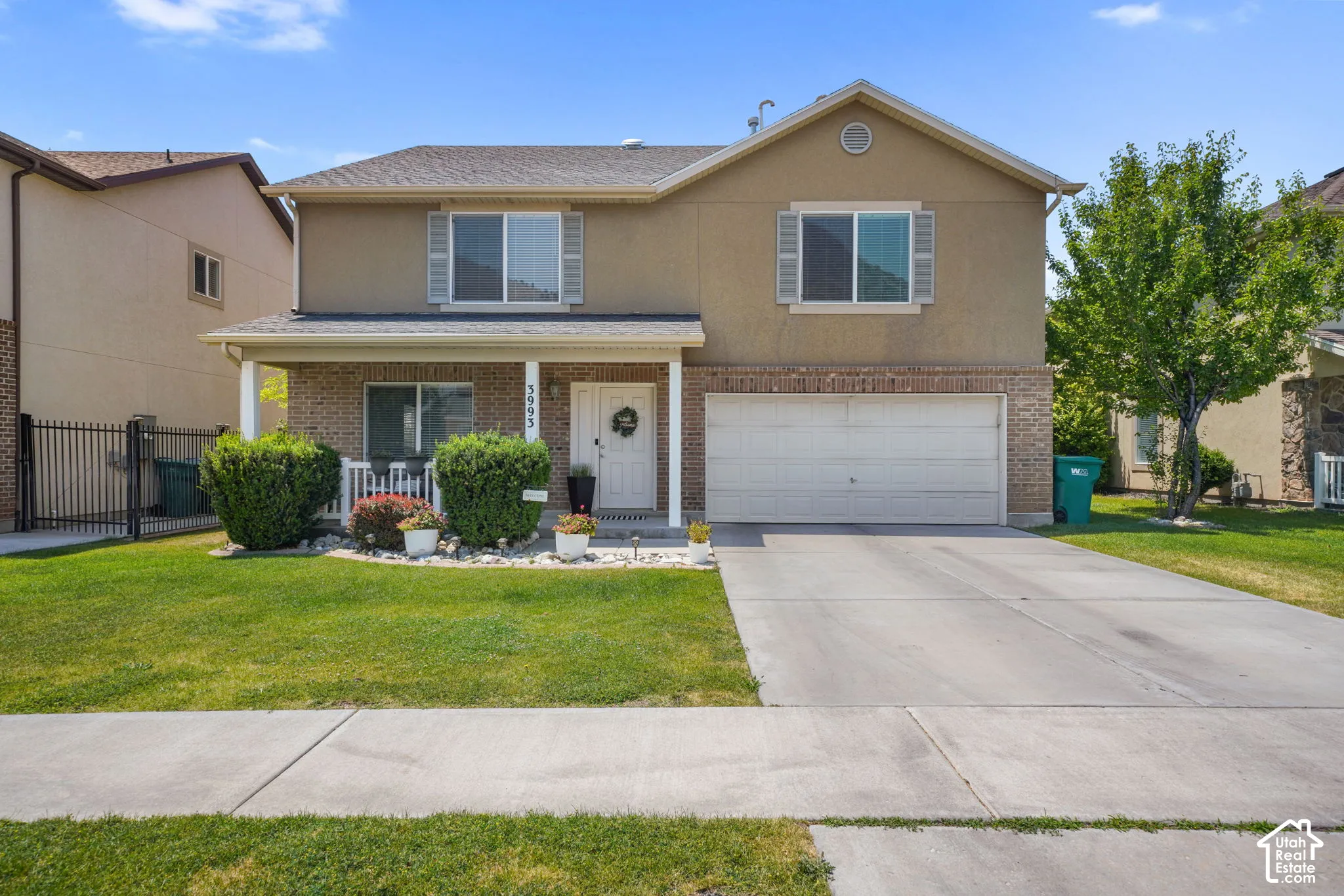 Two-story residence featuring a brick and stucco exterior, an attached two-car garage, and a covered front porch