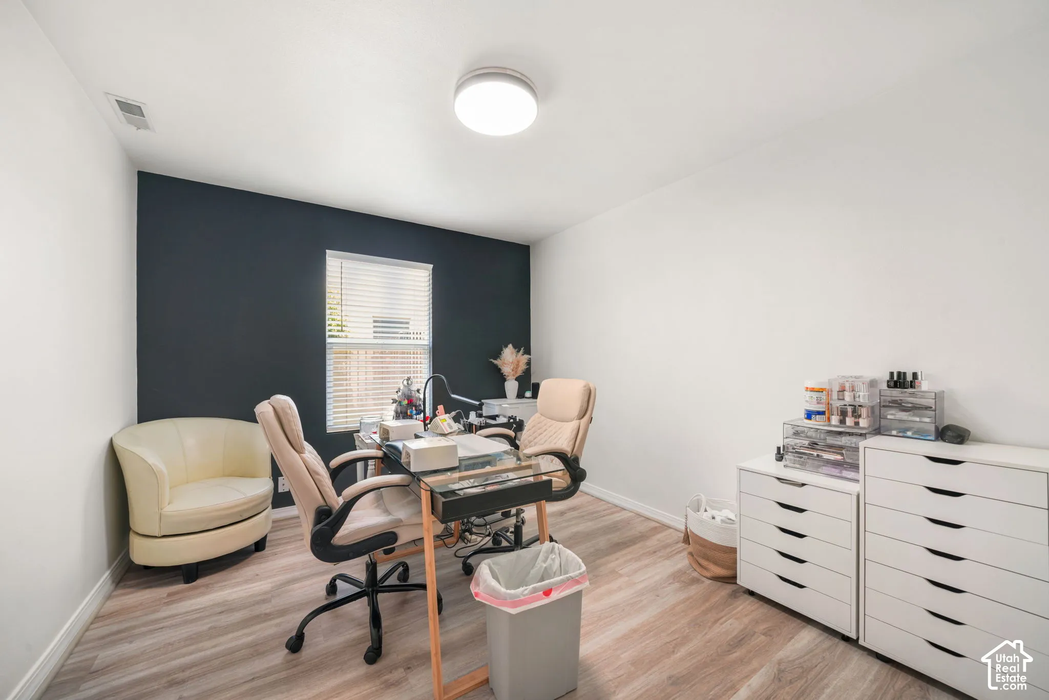 Room featuring wood-finish flooring and a single window with horizontal blinds