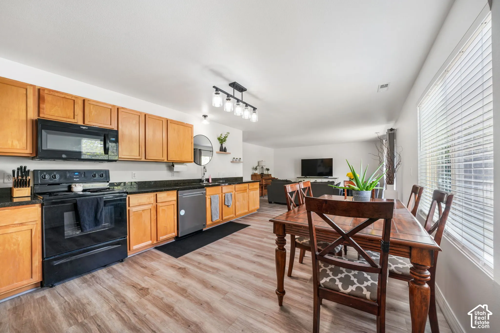 Kitchen featuring wood cabinetry, black appliances, granite-style countertops, and wood-finish flooring