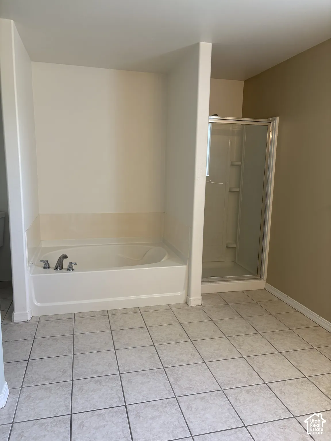 Bathroom featuring a soaking tub with integrated faucet, a separate glass-enclosed shower, and tile flooring