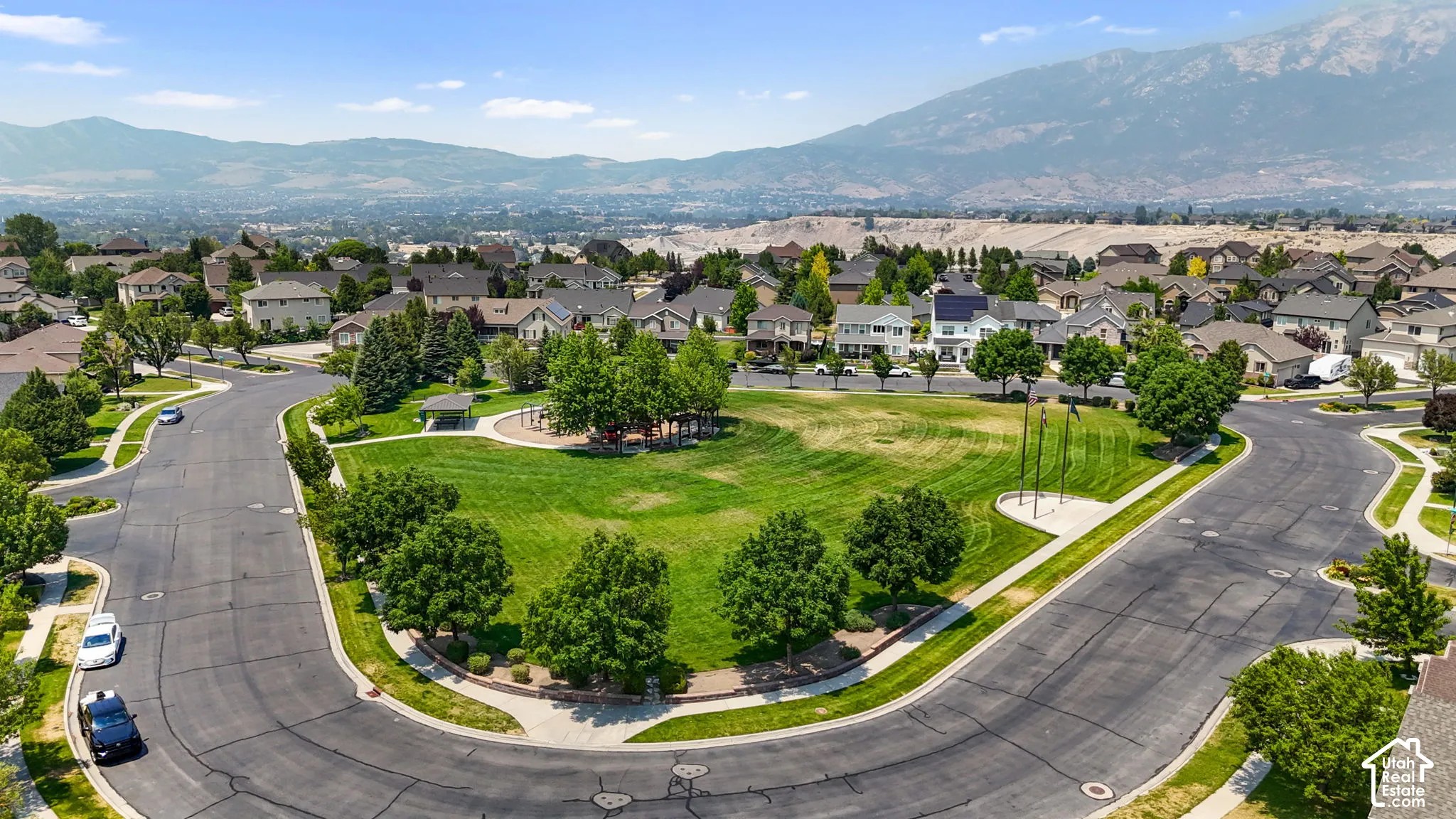 Expansive community green space featuring manicured lawns, mature trees, and a visible playground structure