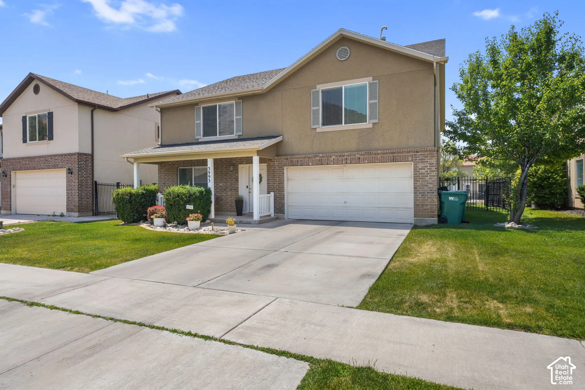 Two-story residence featuring a brick and stucco facade, a covered front porch, and a two-car garage