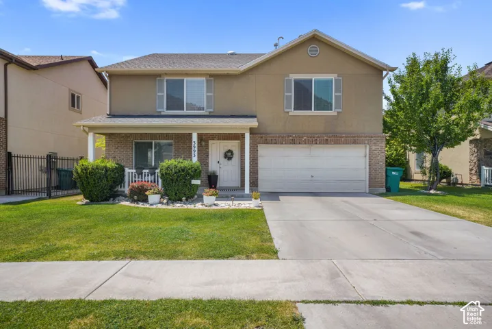 Two-story residence featuring a brick and stucco exterior, an attached two-car garage, and a covered front porch