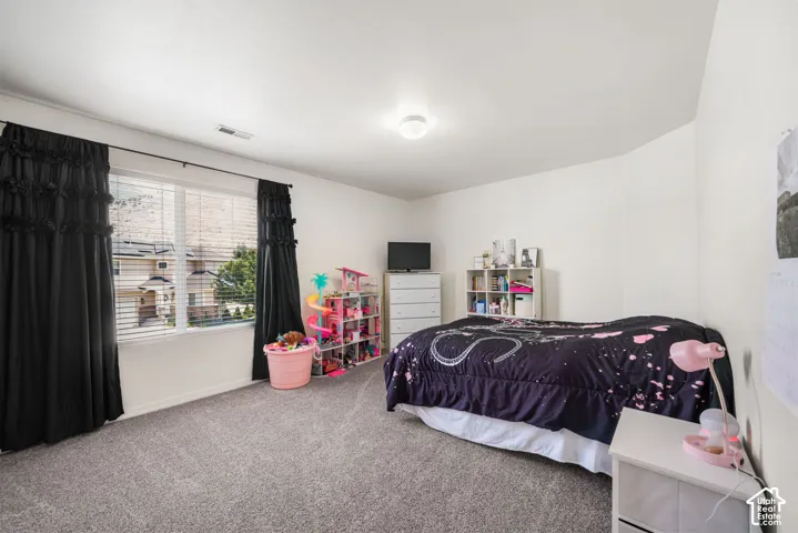 Carpeted room featuring a large window with blinds and dark drapery