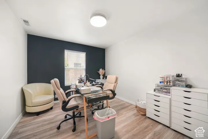 Room featuring wood-finish flooring and a single window with horizontal blinds