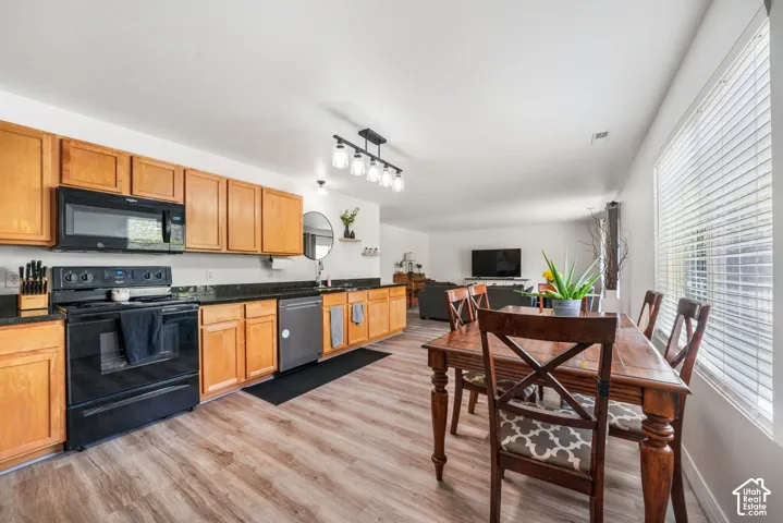 Kitchen featuring wood cabinetry, black appliances, granite-style countertops, and wood-finish flooring