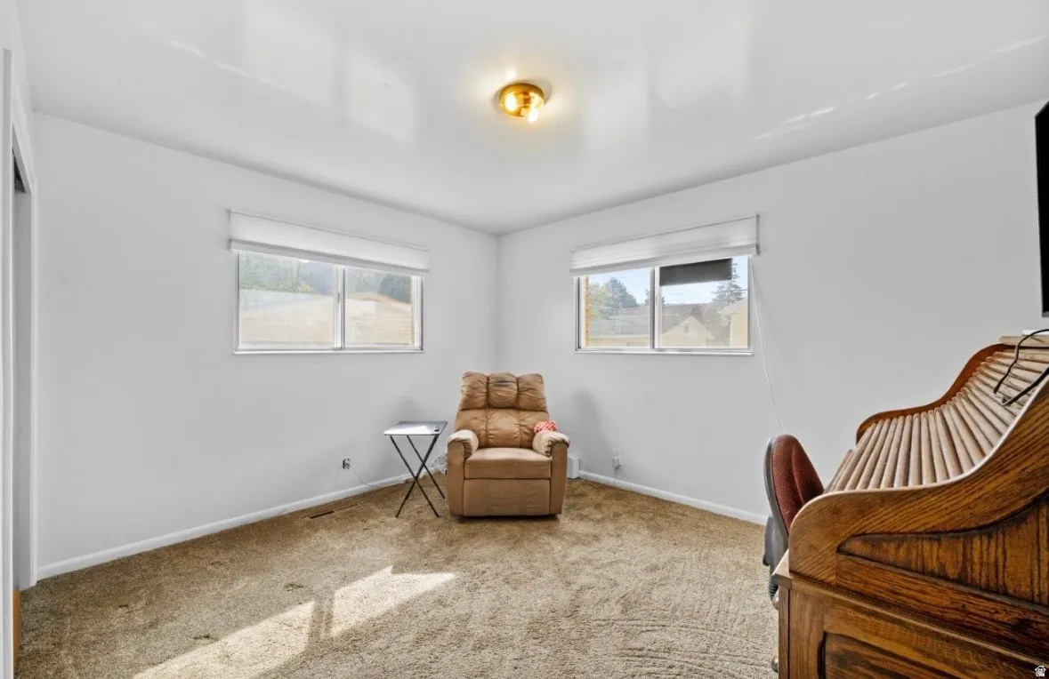 Carpeted room with two windows featuring white blinds