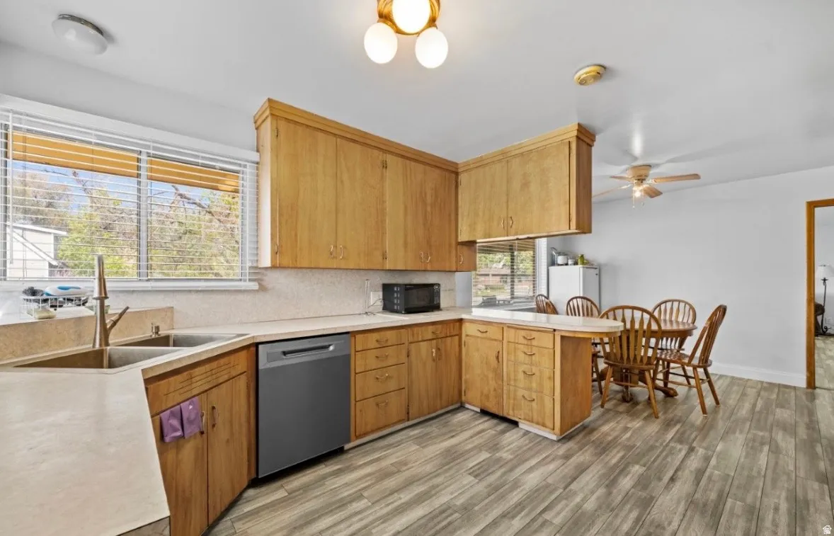 Kitchen featuring wood-finish cabinetry, light-toned countertops, and a double-basin sink